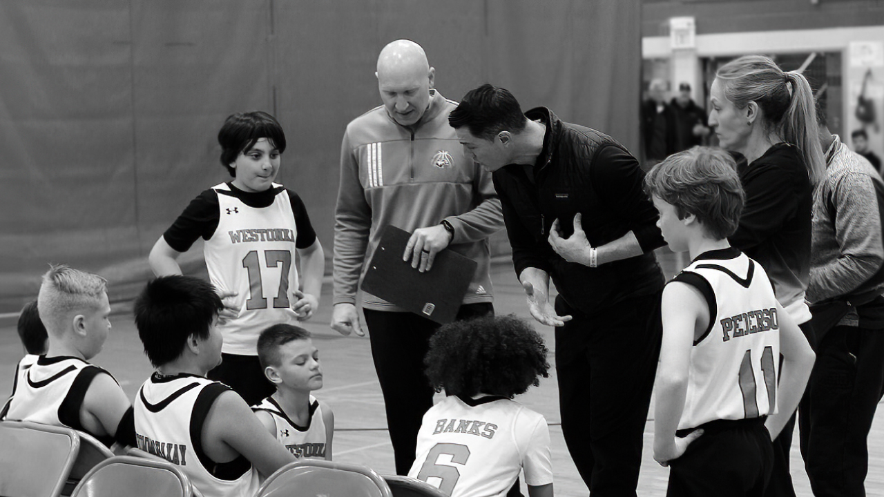 youth basketball players huddled about and listening to their coaches